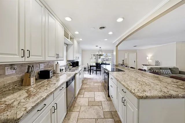 a large kitchen with granite countertop lots of counter space and view of living room