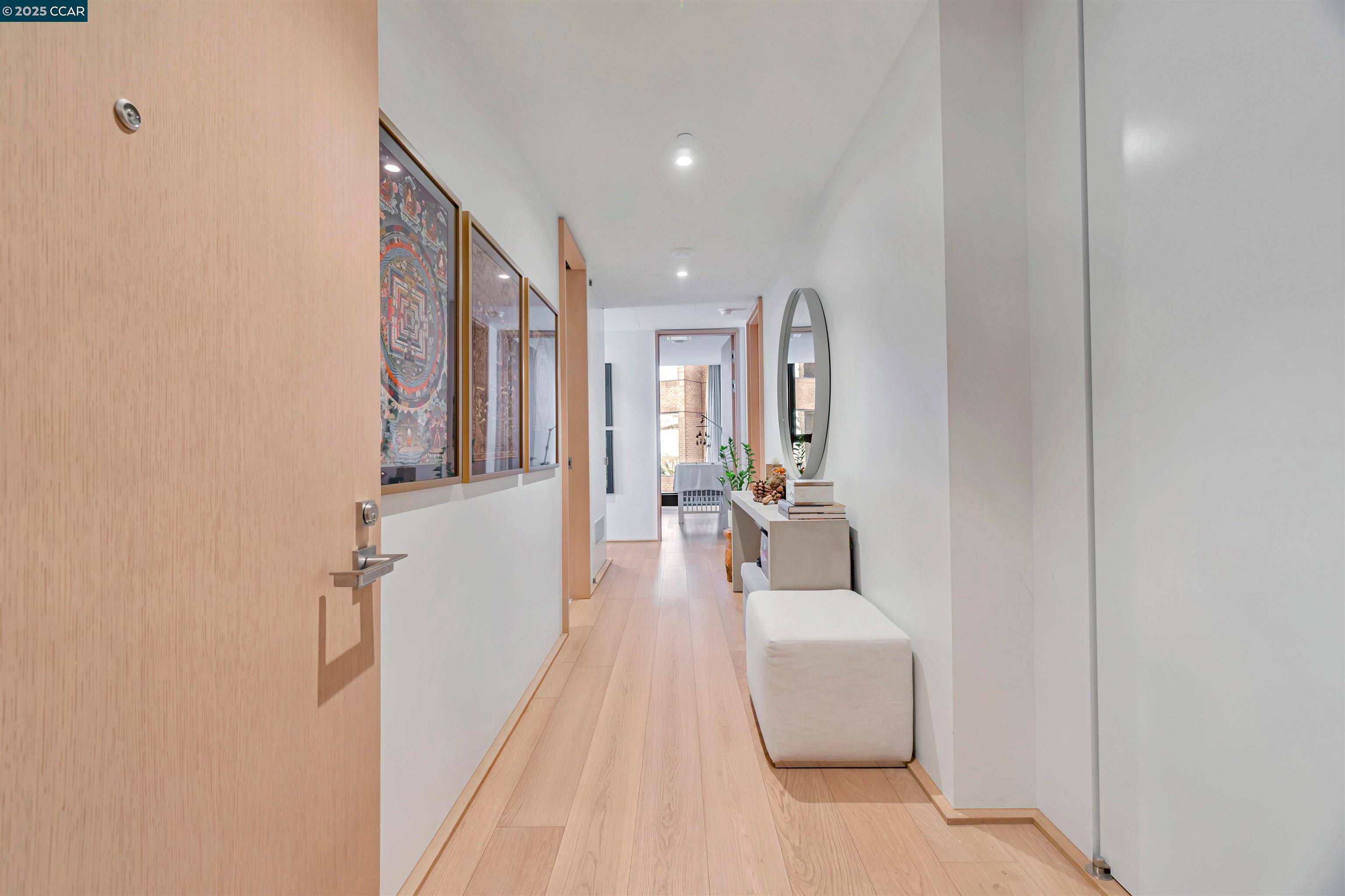 1 Steuart Street, Unit 1103 San Francisco, CA 94105 - Photo 16 of 31 a hallway with white couches and a dining table with wooden floor