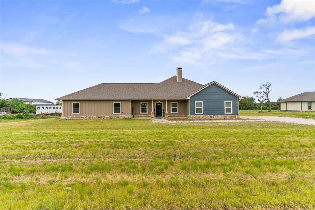 139 Kriston Lane Springtown, TX 76082 - Photo 1 of 39 Ranch-style residence featuring a prominent front porch, a blue-paneled facade, a coordinating brown-toned facade, a central chimney, and a gravel driveway