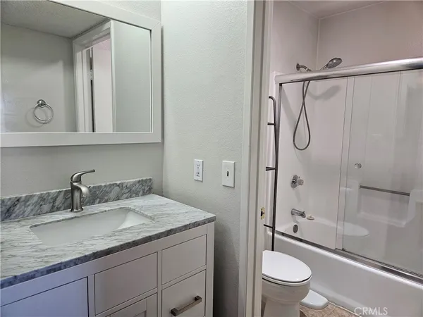 a bathroom with a granite countertop sink a toilet and shower