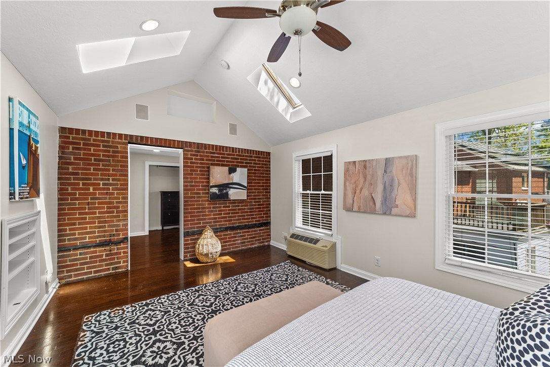 3806 Westwood Road University Heights, OH 44118 - Photo 16 of 41 Interior room featuring a vaulted ceiling with skylights, exposed brick accent wall, and dark wood-finish flooring