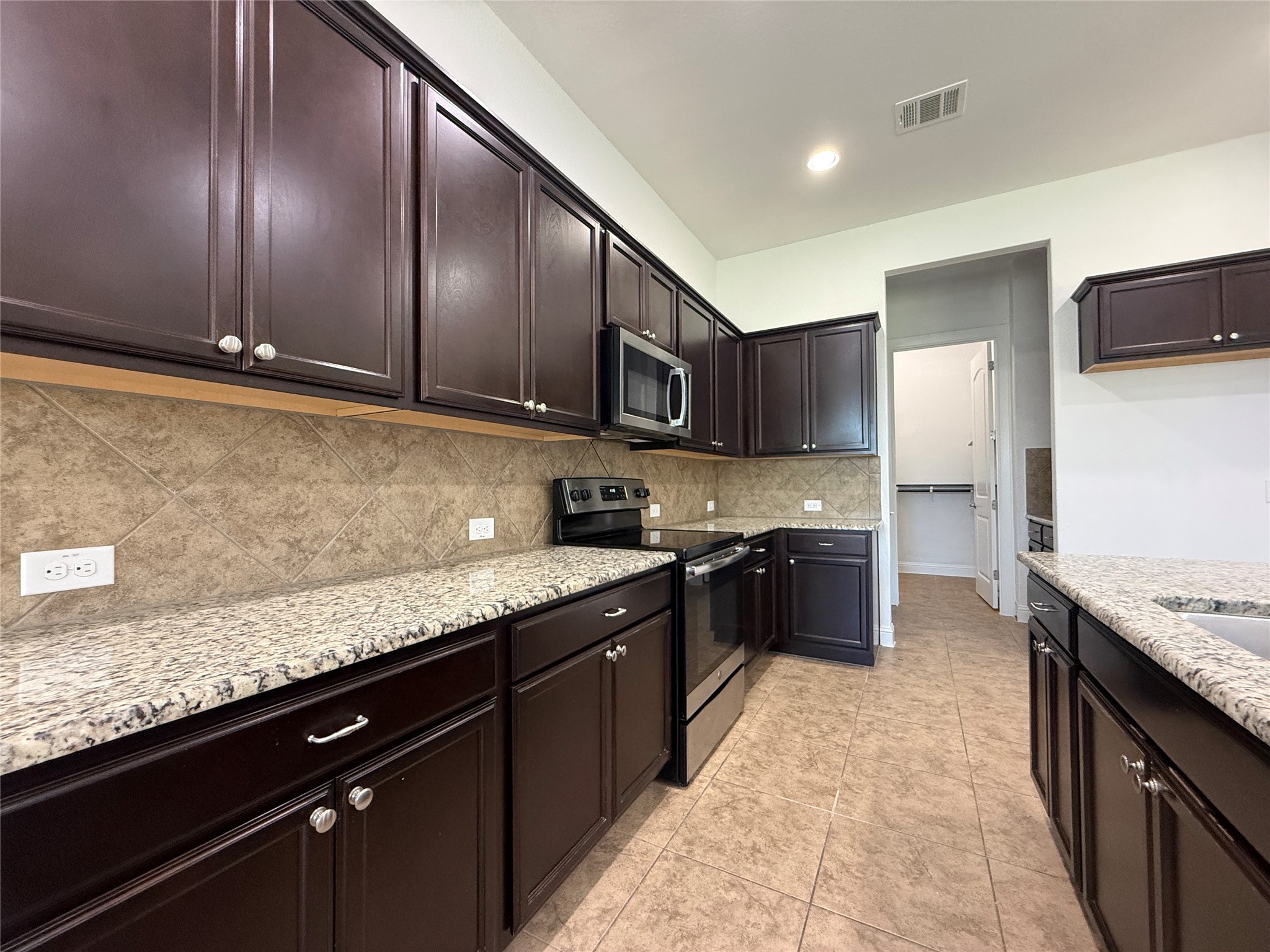 1512 Long Shadow Lane Georgetown, TX 78628 - Photo 9 of 19 a kitchen with stainless steel appliances granite countertop wooden cabinets a stove top oven a sink and dishwasher