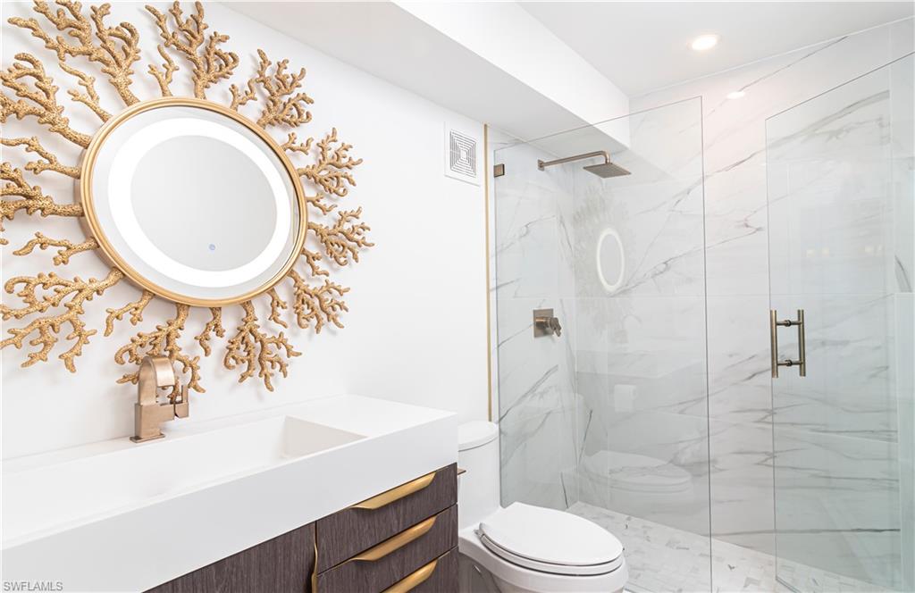 1222 Gordon Drive, Unit 4 Naples, FL 34102 - Photo 17 of 20 a bathroom with a toilet sink mirror vanity and shower