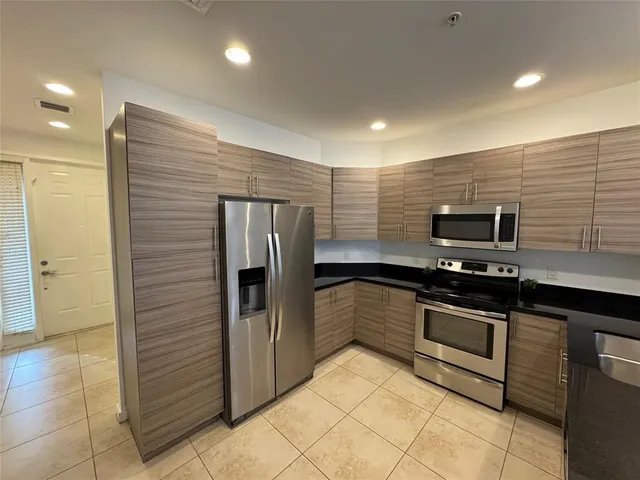 a kitchen with stainless steel appliances granite countertop a sink a stove and a refrigerator