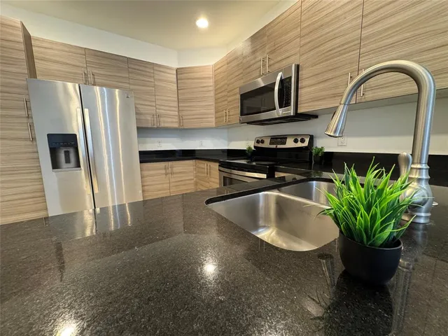 a kitchen with stainless steel appliances a sink a microwave a refrigerator and a stove