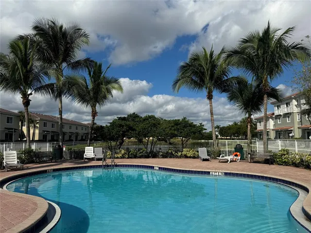 a view of swimming pool with table and chairs water fall and palm tree