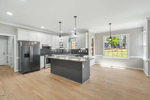 a kitchen with stainless steel appliances granite countertop a refrigerator a sink a oven and a wooden floors