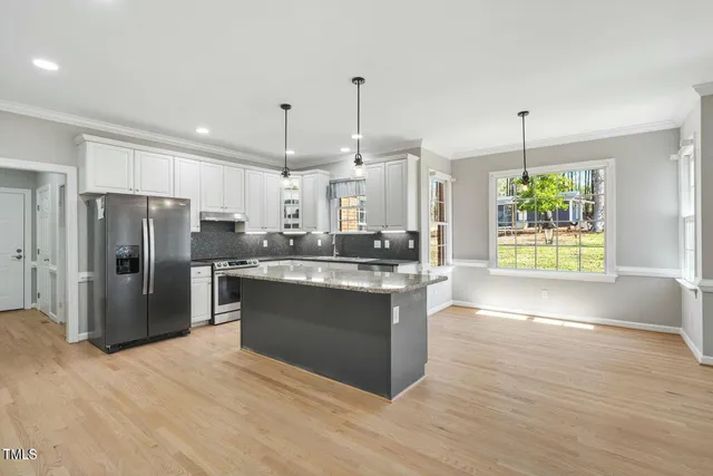 a kitchen with stainless steel appliances granite countertop a refrigerator a sink a oven and a wooden floors