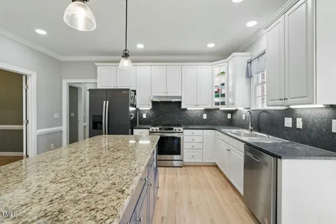 a kitchen with granite countertop a sink stainless steel appliances and cabinets