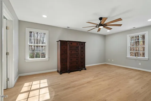 a view of empty room with wooden floor and fan