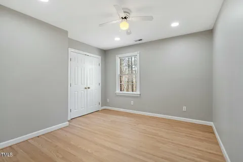 a view of empty room with wooden floor and fan