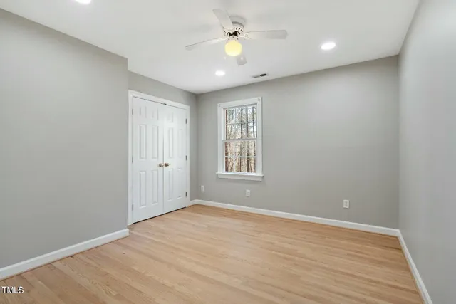 a view of empty room with wooden floor and fan