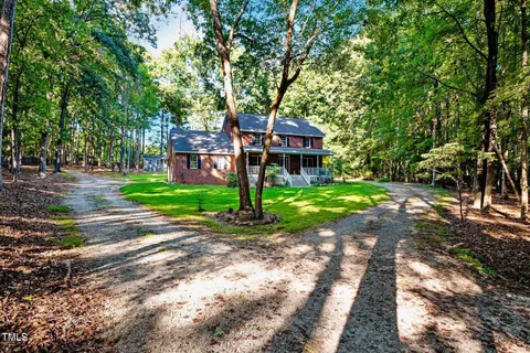 a front view of a house with a yard and large trees