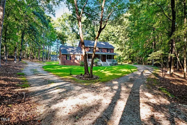 a front view of a house with a yard and large trees