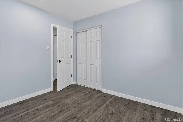 a view of an empty room with wooden floor and window