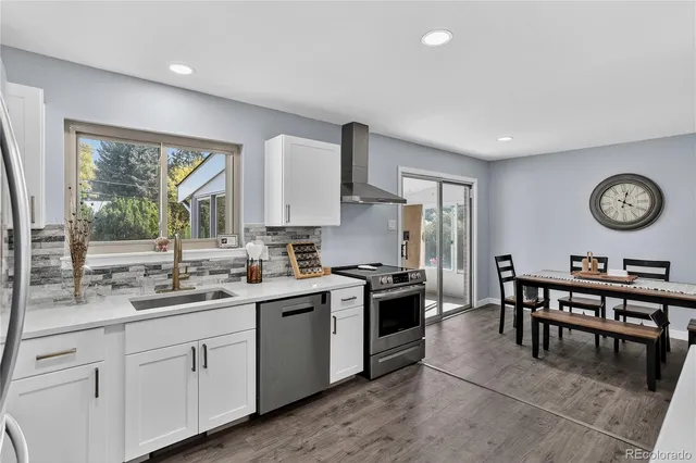 a kitchen with a sink appliances cabinets and a large window