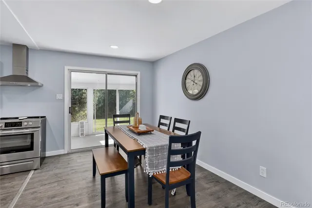 a kitchen with stainless steel appliances granite countertop a stove a sink dishwasher a refrigerator white cabinets and wooden floor next to a window