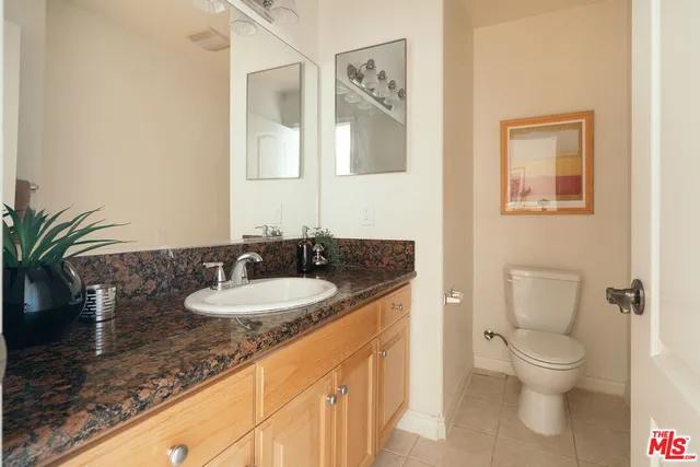 a bathroom with a granite countertop sink a large mirror and a toilet