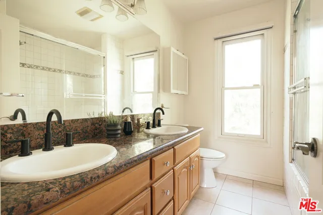 a bathroom with a sink double vanity granite tub shower and mirror
