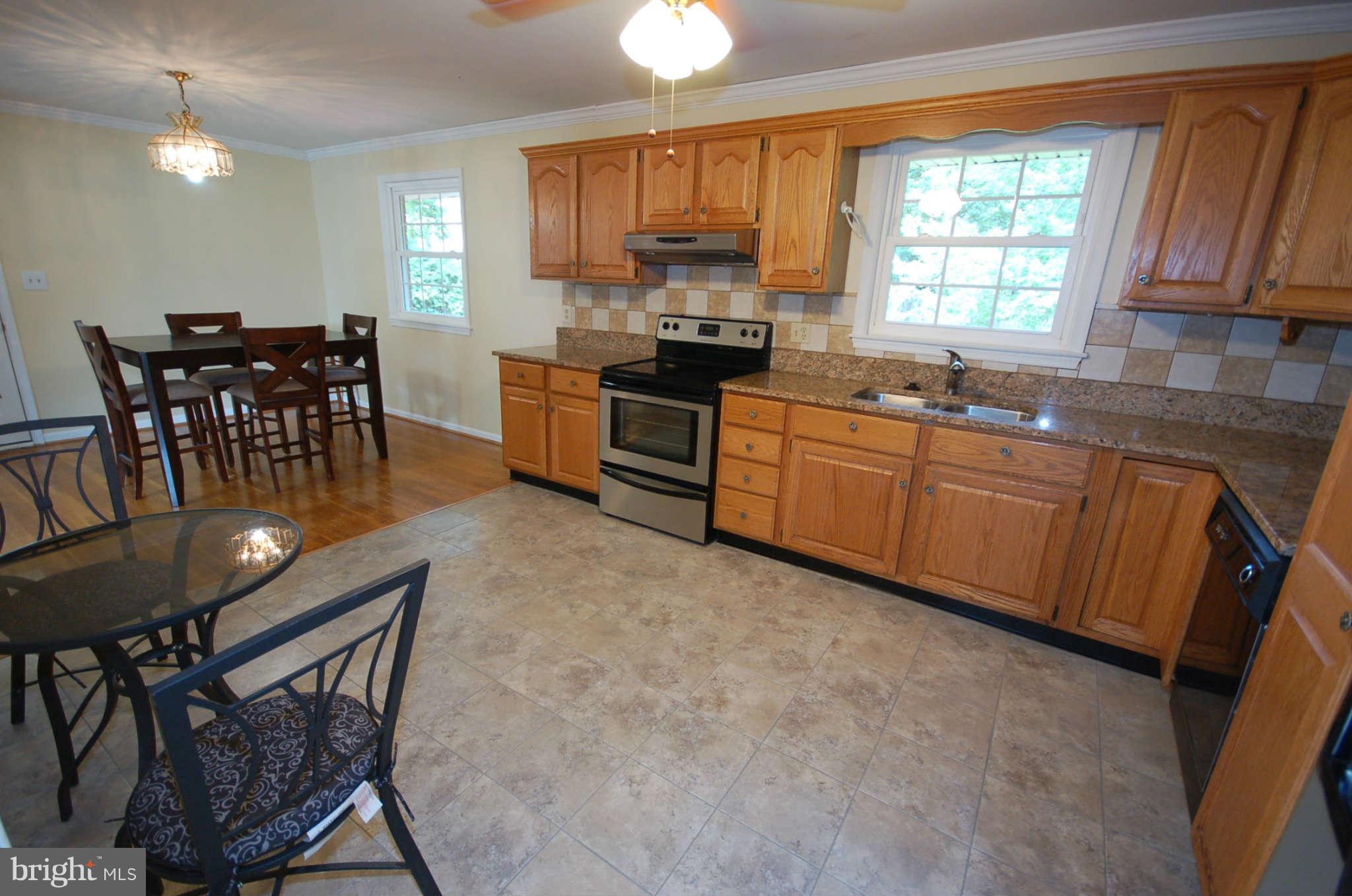 3132 Castleleigh Road Silver Spring, MD 20904 - Photo 7 of 25 a kitchen with stainless steel appliances granite countertop wooden cabinets a stove a sink a dining table and chairs