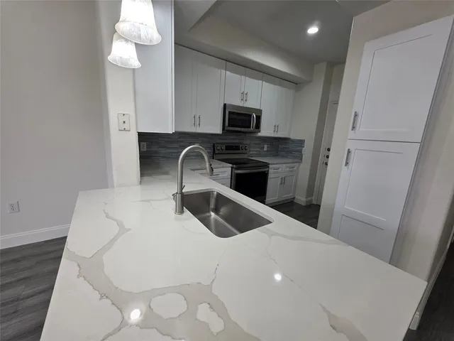 a kitchen with stainless steel appliances a stove a sink a microwave and cabinets