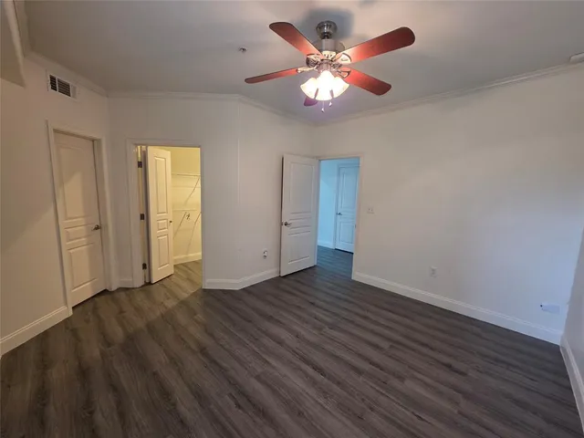 an empty room with wooden floor and a ceiling fan