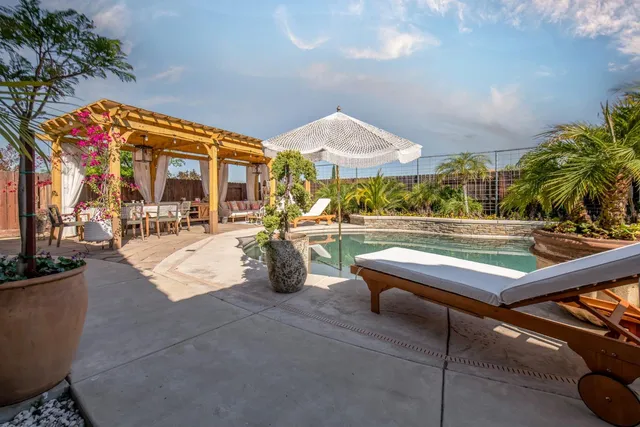 a patio with a table and chairs and potted plants