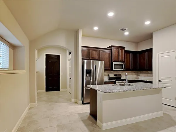 a kitchen with stainless steel appliances granite countertop a refrigerator a sink a stove and a refrigerator with wooden floor