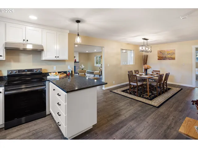 a kitchen with stainless steel appliances kitchen island granite countertop a sink dishwasher a stove and a dining table with wooden floor