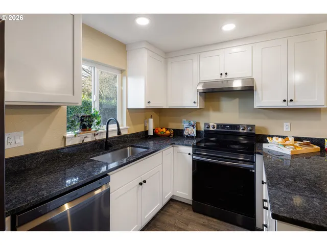 a kitchen with stainless steel appliances granite countertop a stove a sink and a white cabinets