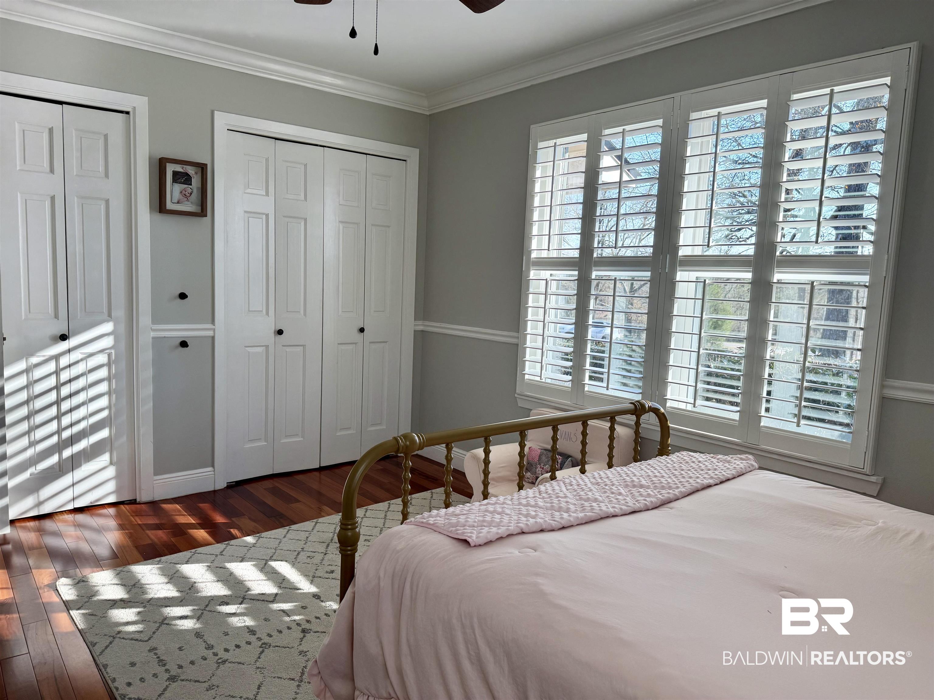 5646 Foshee Road Brewton, AL 36426 - Photo 19 of 37 Bedroom with multiple closets, dark wood finished floors, ornamental molding, and ceiling fan