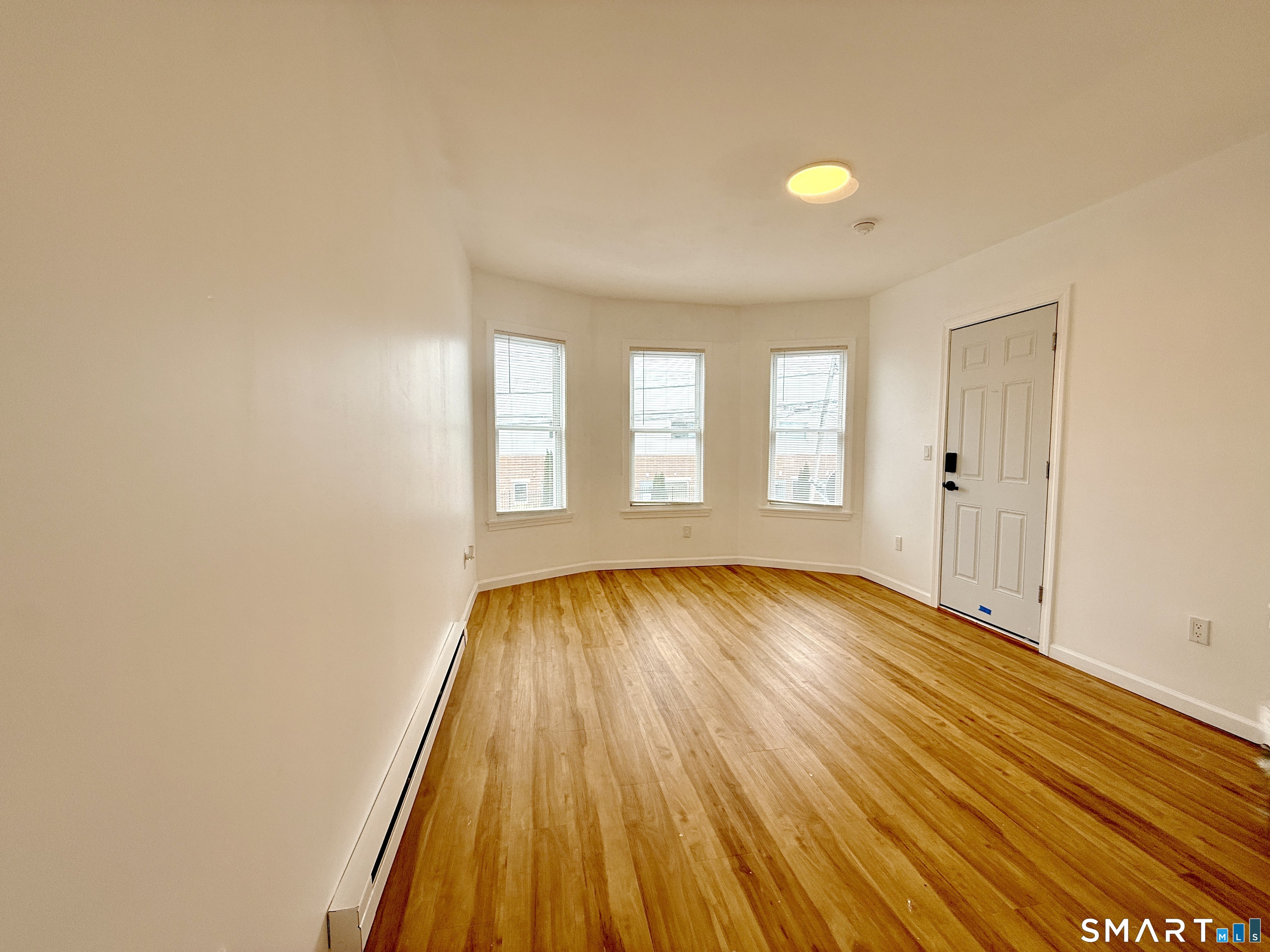 70 Lindley Street Bridgeport, CT 06604 - Photo 3 of 8 an empty room with wooden floor and windows