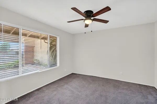 an empty room with a window and a fan