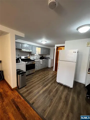 a kitchen with a sink a stove top oven a refrigerator and white cabinets