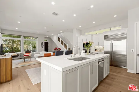 a large white kitchen with a large window and stainless steel appliances
