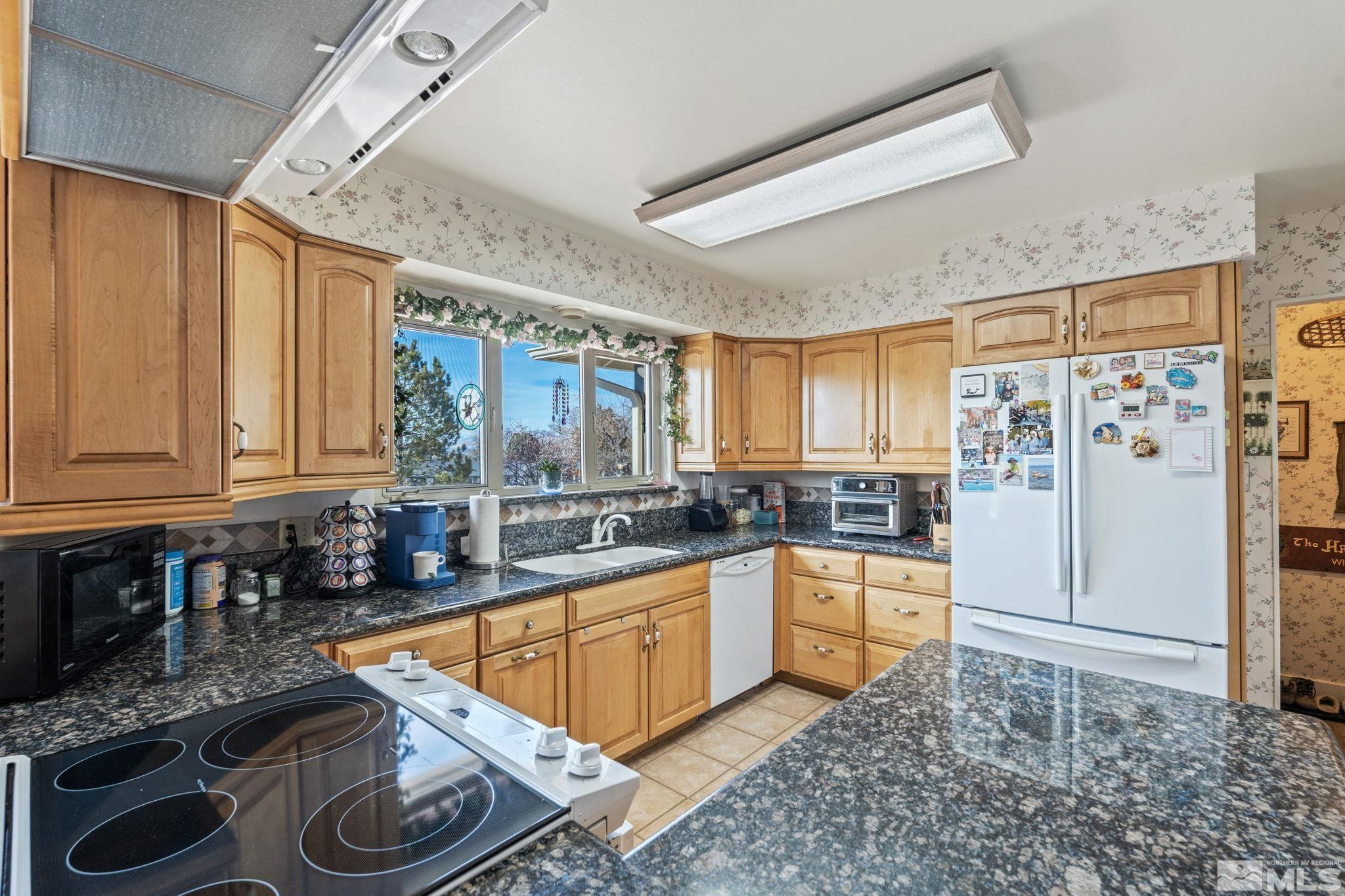 14440 Rim Rock Drive Reno, NV 89521 - Photo 6 of 39 a kitchen with stainless steel appliances granite countertop a stove a sink and a refrigerator