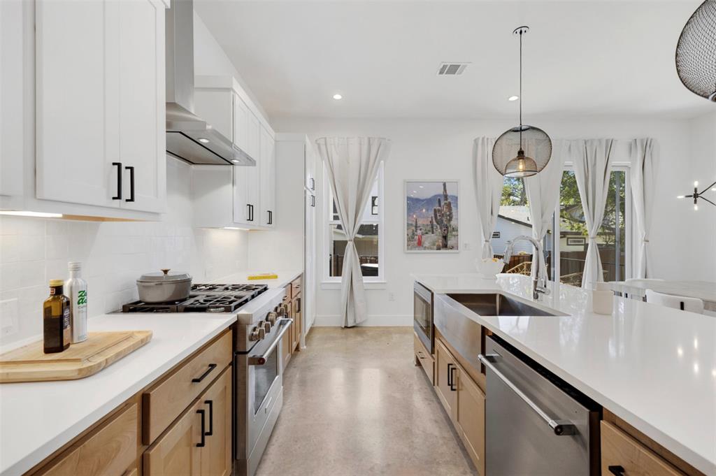 5007 Lott Avenue, Unit 1 Austin, TX 78721 - Photo 5 of 24 A well-lit, open-concept kitchen boasts a gas range, modern hood, and a spacious island with a farm sink.