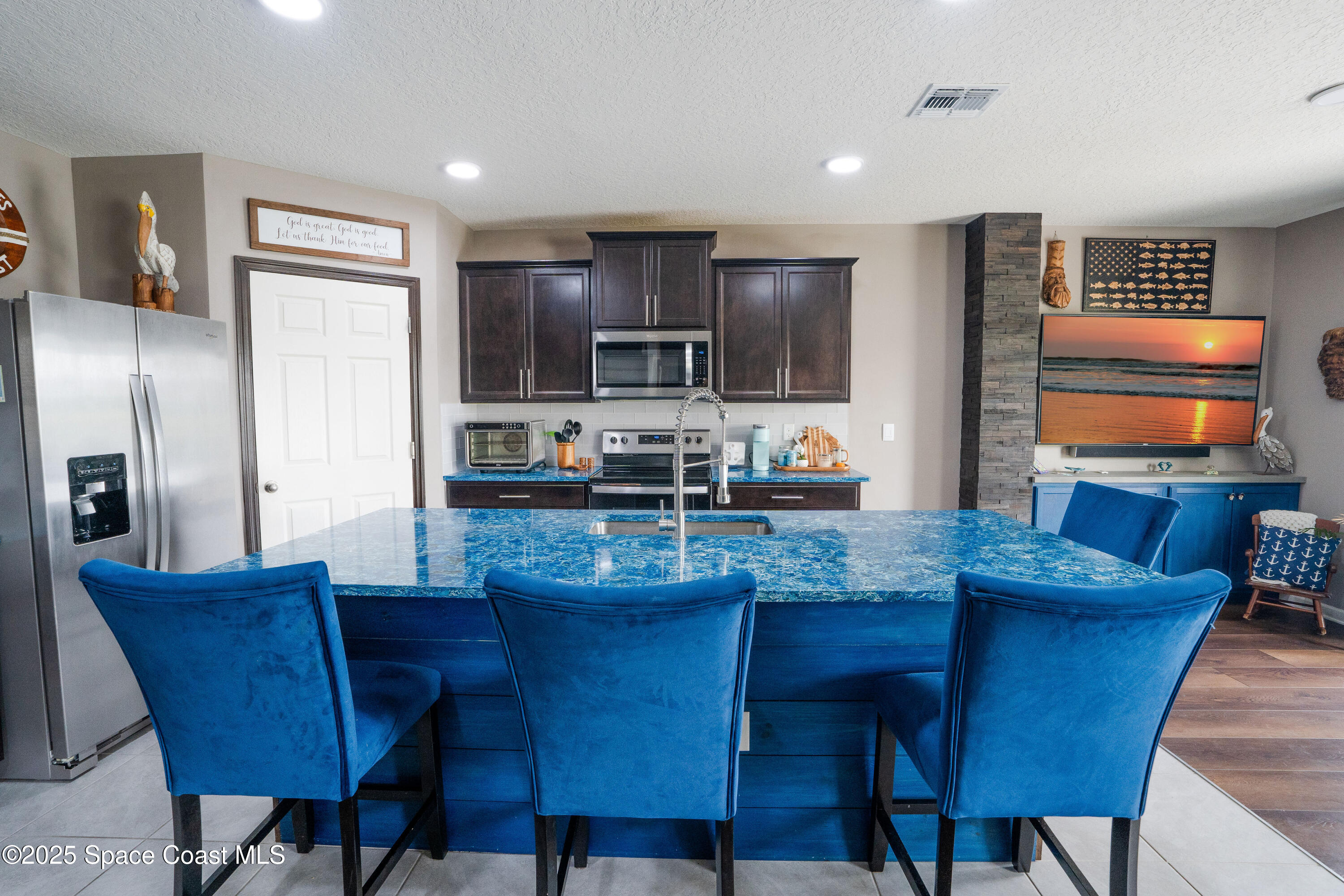 3409 Burrowing Owl Mims, FL 32754 - Photo 12 of 36 a kitchen with stainless steel appliances granite countertop a dining table chairs refrigerator and a sink
