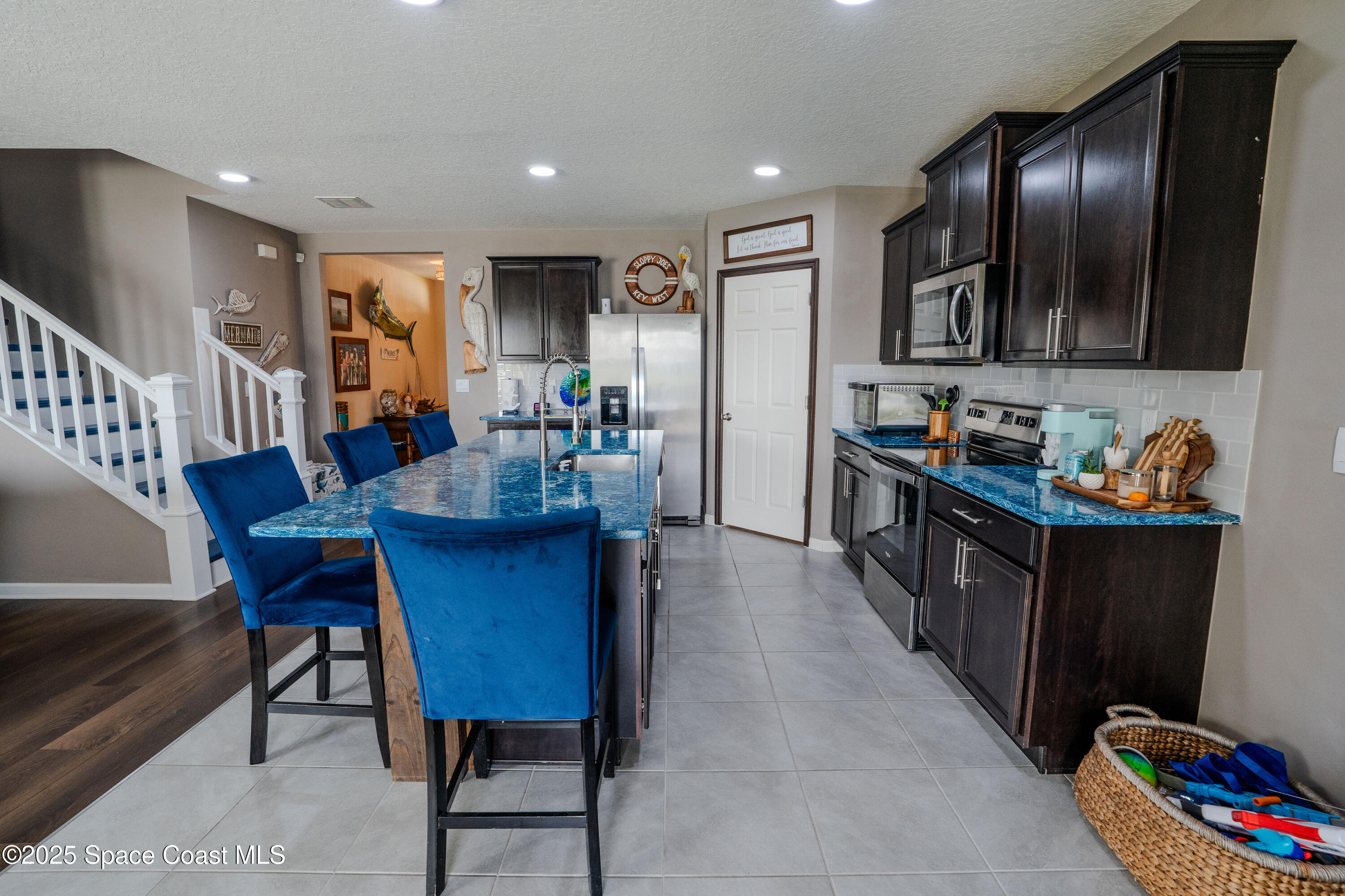 3409 Burrowing Owl Mims, FL 32754 - Photo 10 of 36 a kitchen with stainless steel appliances kitchen island granite countertop a dining table chairs sink and wooden floor