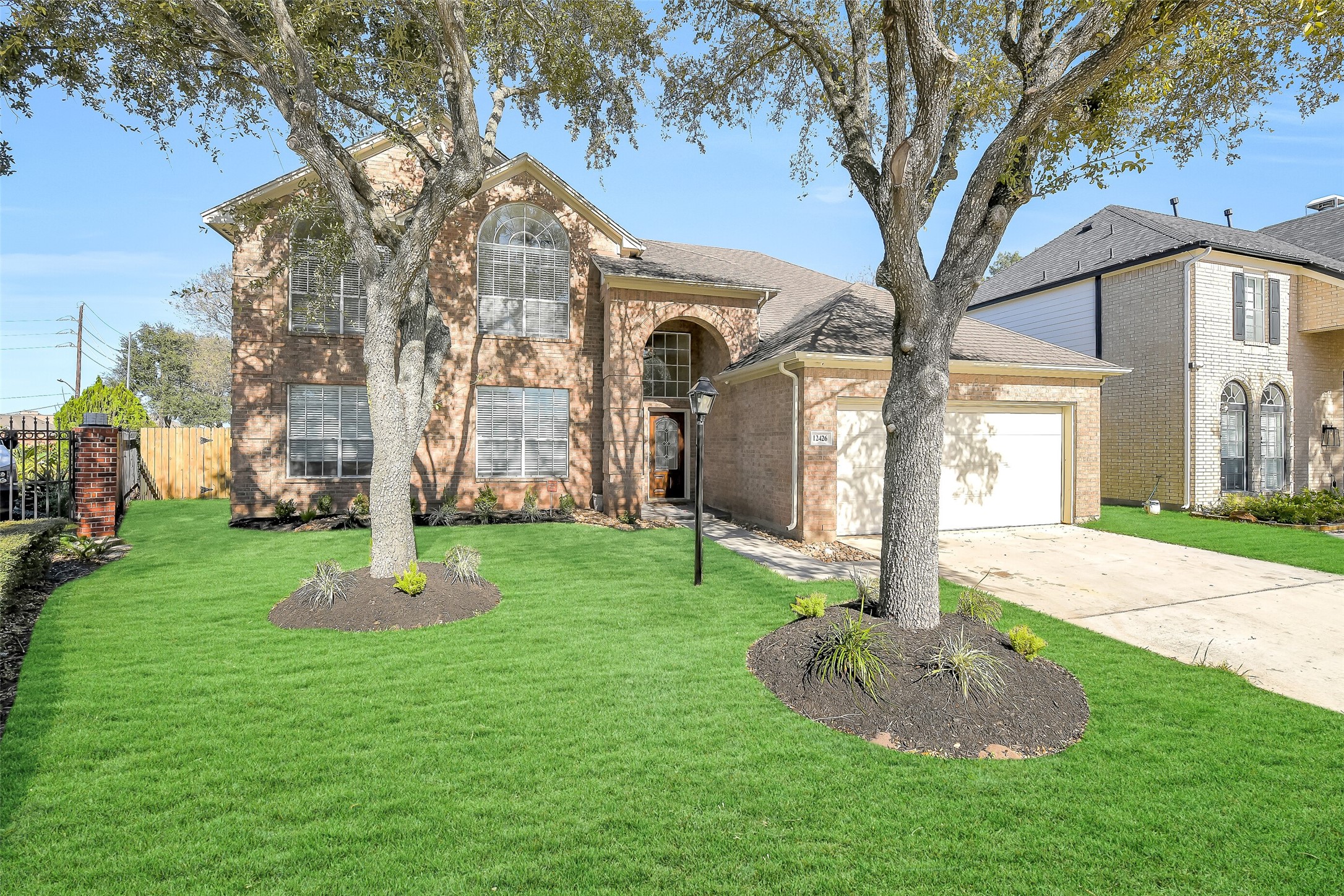 a front view of a house with a yard and large tree
