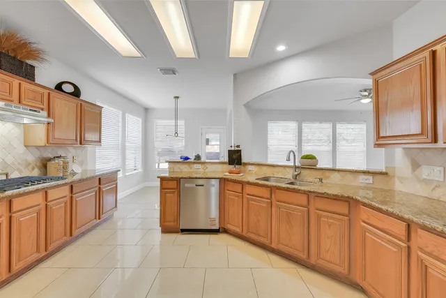 a large kitchen with stainless steel appliances granite countertop a sink and dishwasher a stove top oven with wooden floor