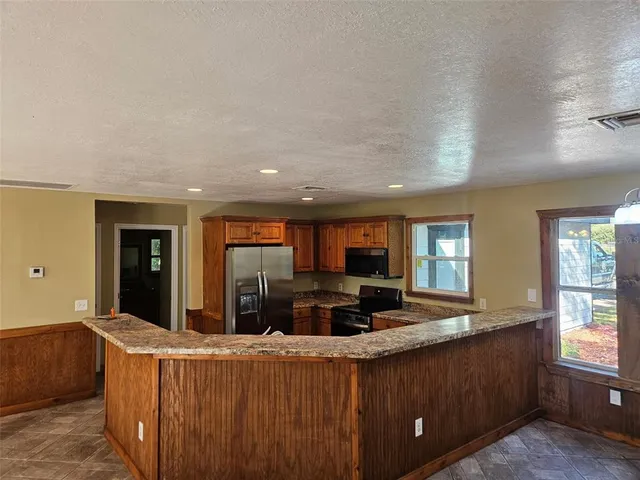 a kitchen with kitchen island granite countertop a sink and a refrigerator