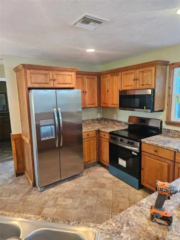 a kitchen with granite countertop a refrigerator and a stove top oven