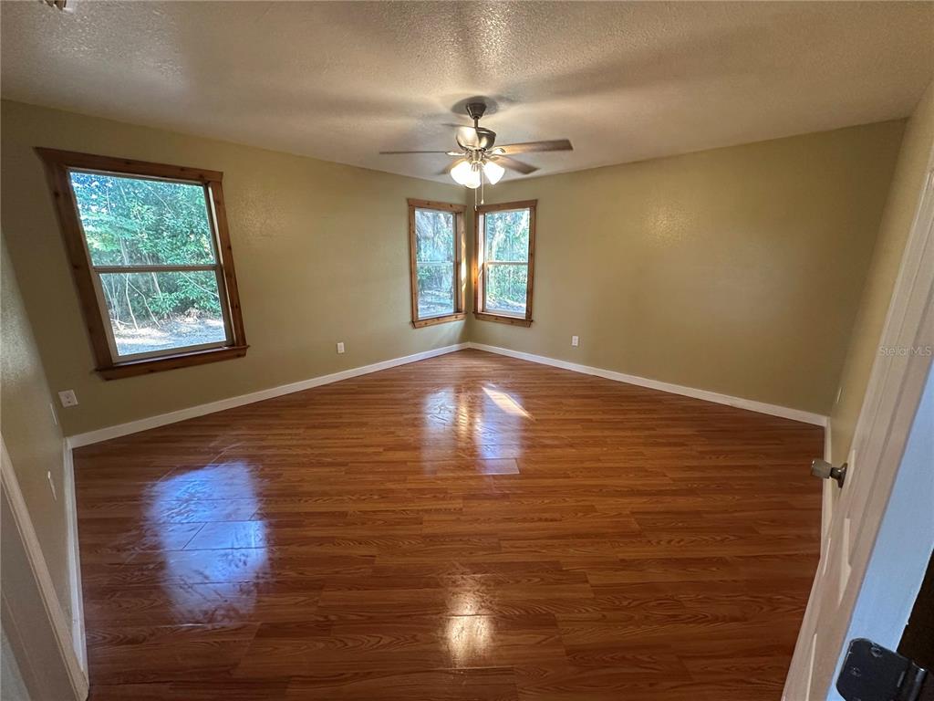 12022 Southeast Sunset Harbor Road Weirsdale, FL 32195 - Photo 7 of 17 a view of an empty room with window and chandelier fan