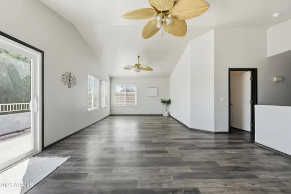 a view of an empty room with a window and wooden floor
