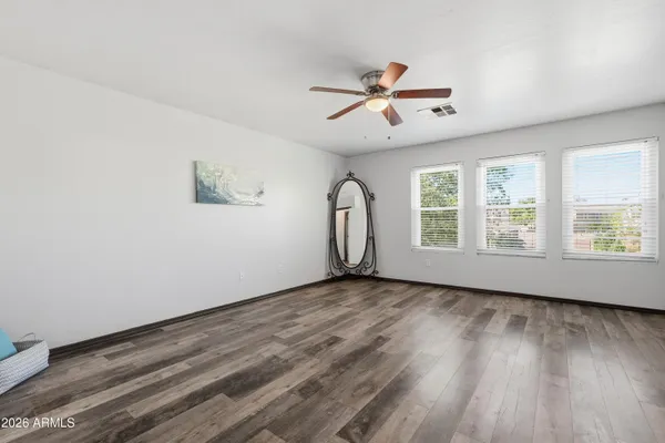 a view of empty room with wooden floor and fan