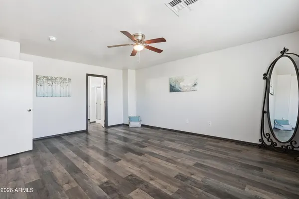 a view of an empty room with window a ceiling fan and wooden floor