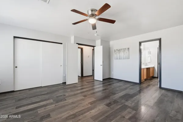 an empty room with wooden floor mirror and windows