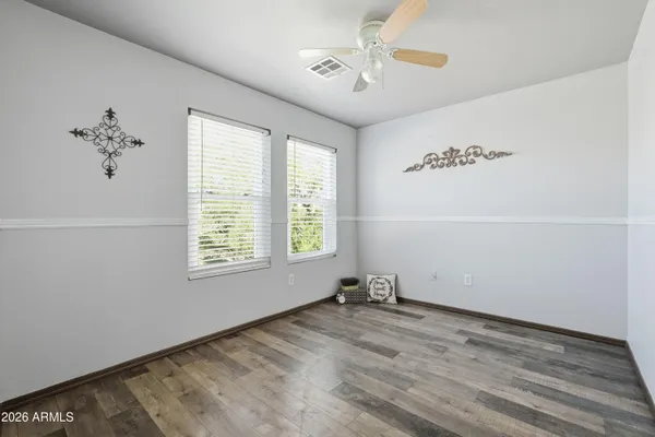 an empty room with a ceiling fan and wooden floor