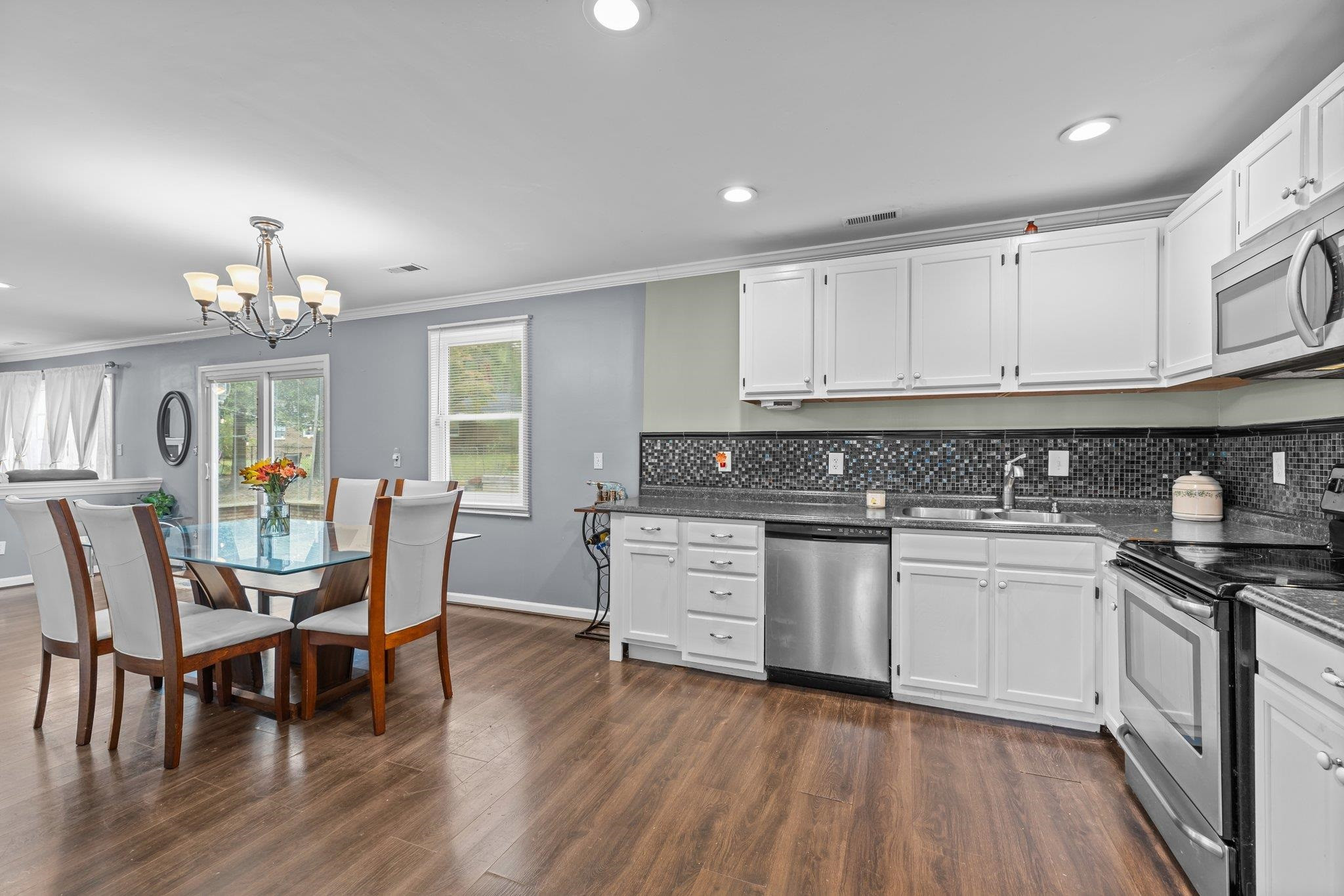 2208 Dobbin Place Raleigh, NC 27604 - Photo 11 of 42 a kitchen with granite countertop wooden floors white cabinets and appliances
